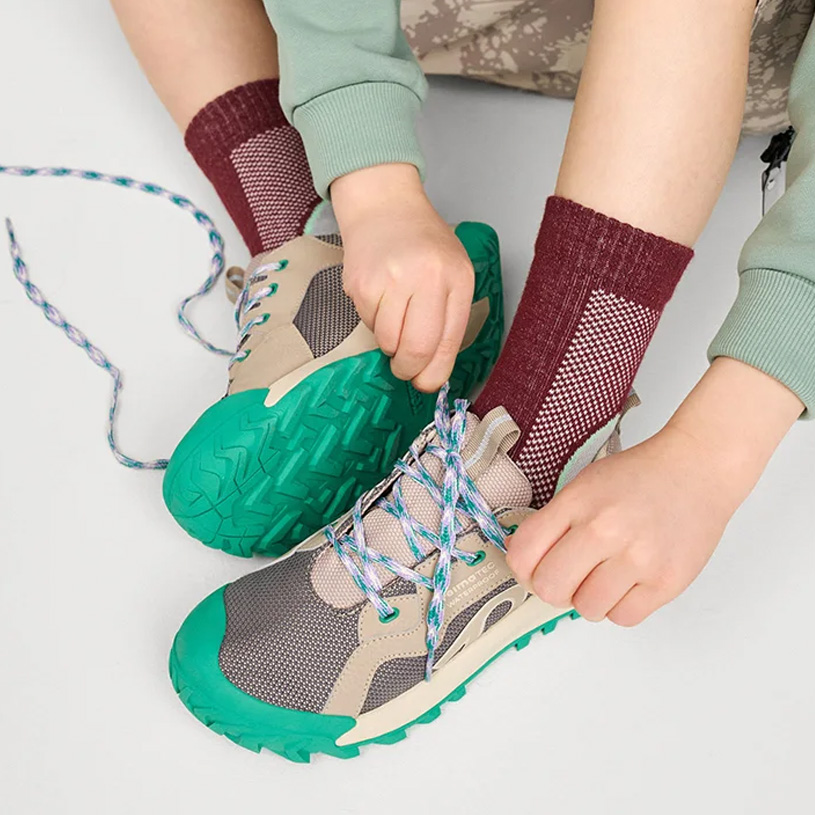 Kinder braune Schuhe mit Klettverschluss und bunte Hose.