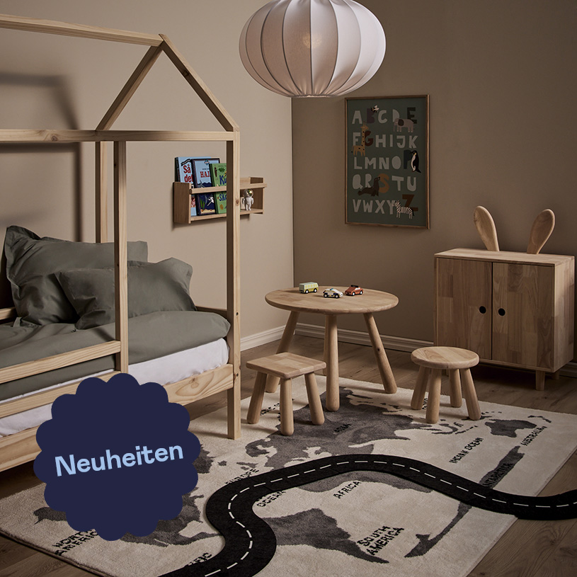 Kinderzimmer mit Holztisch, Stuhl und Bett, Weltkartenteppich.