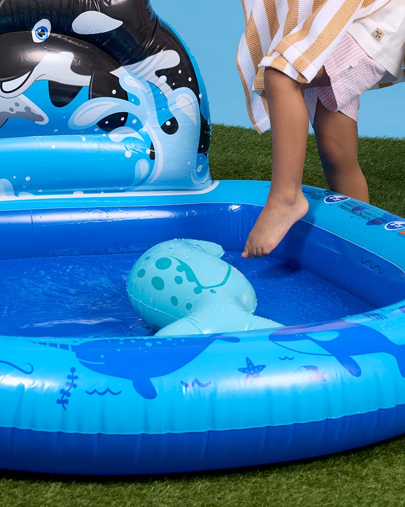 Mädchen mit Schwimmring in einem blau-weißen Pool im Freien.