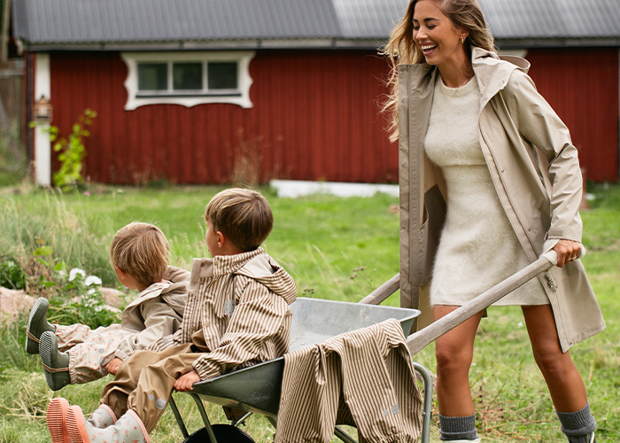 Eine Frau schiebt eine Schubkarre mit zwei Kindern, mit dem Text 'Kenza X Viking'.