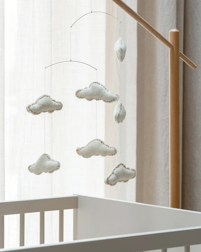 Baby-Mobile mit Stofftieren und grünen Herzen.