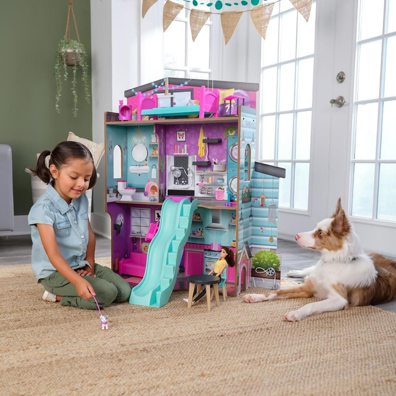 Mädchen und Hund spielen am Puppenhaus auf dem Boden.