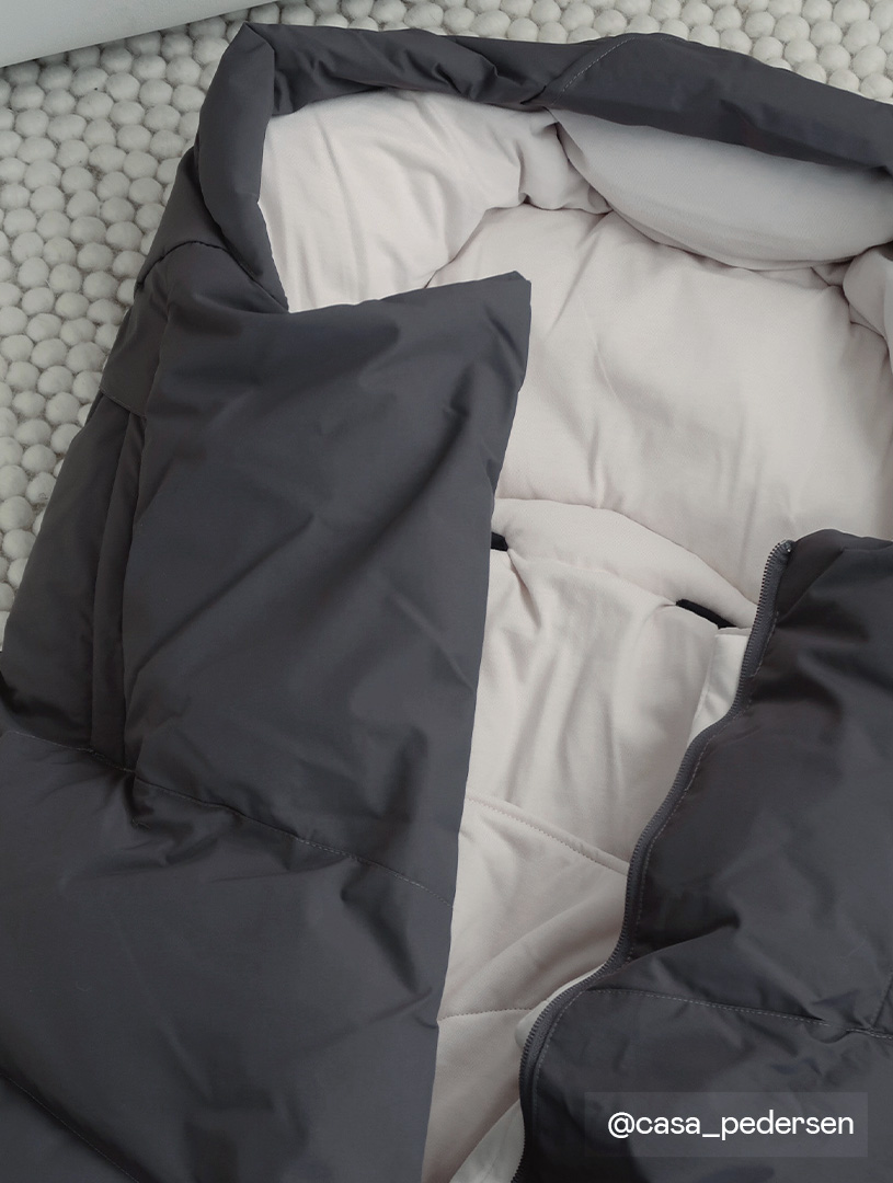 Schwarzer und weißer Kinderwagensack auf grauem Untergrund.