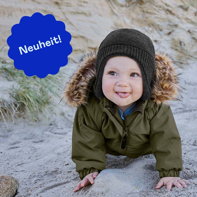 Baby in Winterkleidung krabbelt am Sandstrand, Text "Neuheit!"