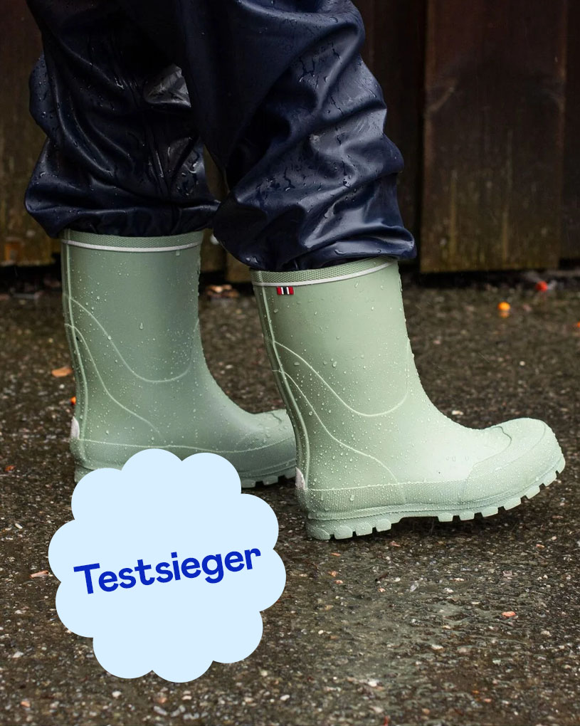 Rosa Gummistiefel mit Wassertropfen und dem Text 'Testsieger'.