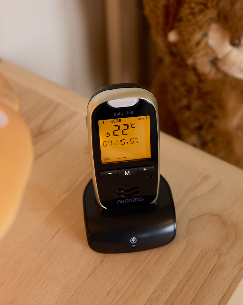 Schlafendes Baby im Kinderbett mit Babyphone auf dem Nachttisch.