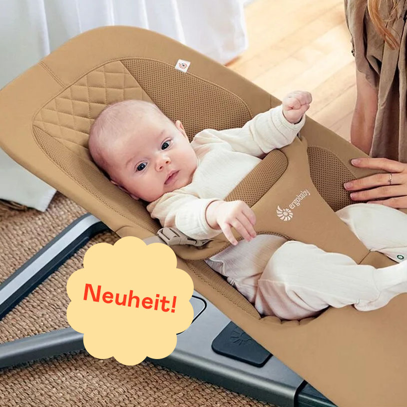 Baby in beige Babywippe mit Text „Neuheit!“ in lila Sprechblase.