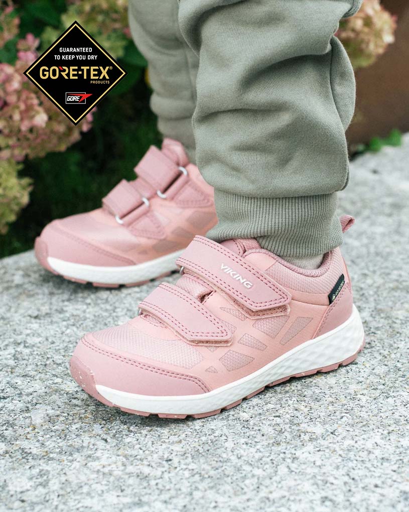 Blaue Kinderschuhe auf Kopfsteinpflaster, Jeans am Bein.