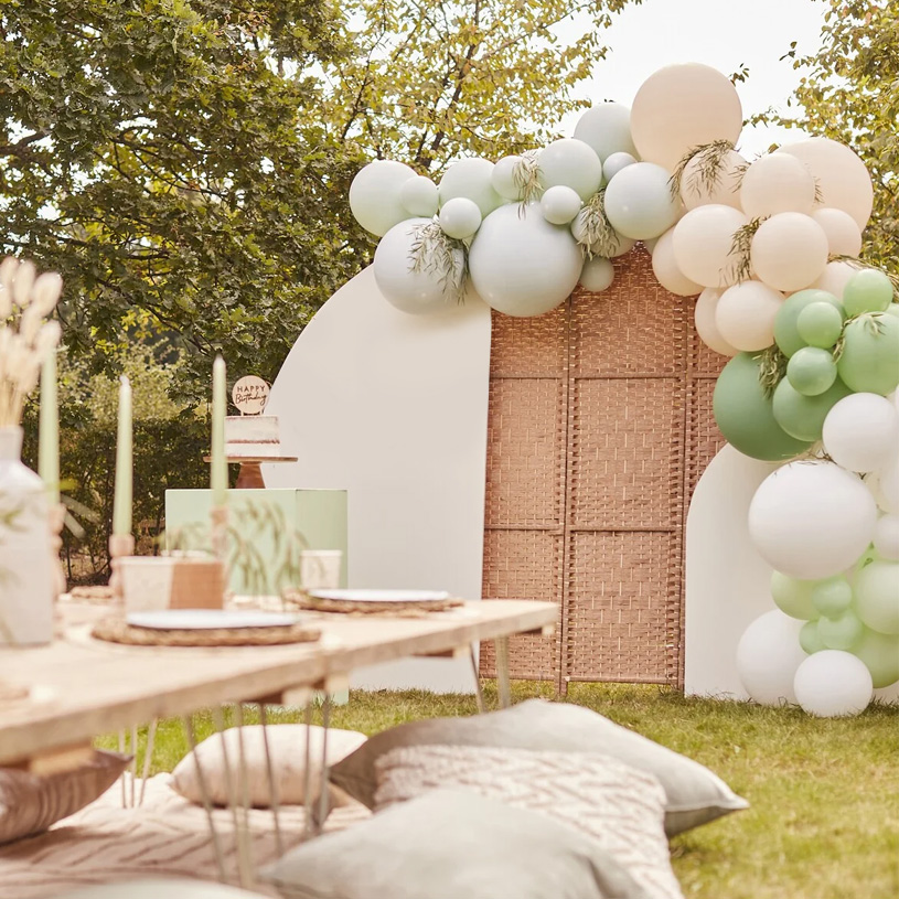 Gartenfest mit pastellfarbenen Luftballons und gedecktem Tisch auf dem Rasen.