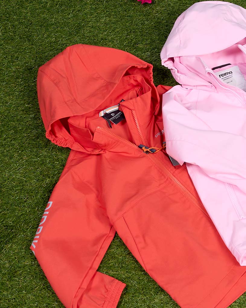 Kind mit langem Haar und Kappe in beiger Didriksonsjacke draußen.