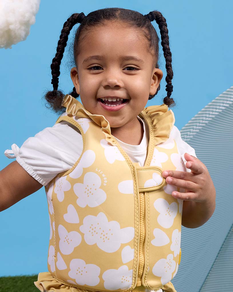 Blondes Kind mit Schwimmflügel mit Möwenmotiv sitzt am Pool.