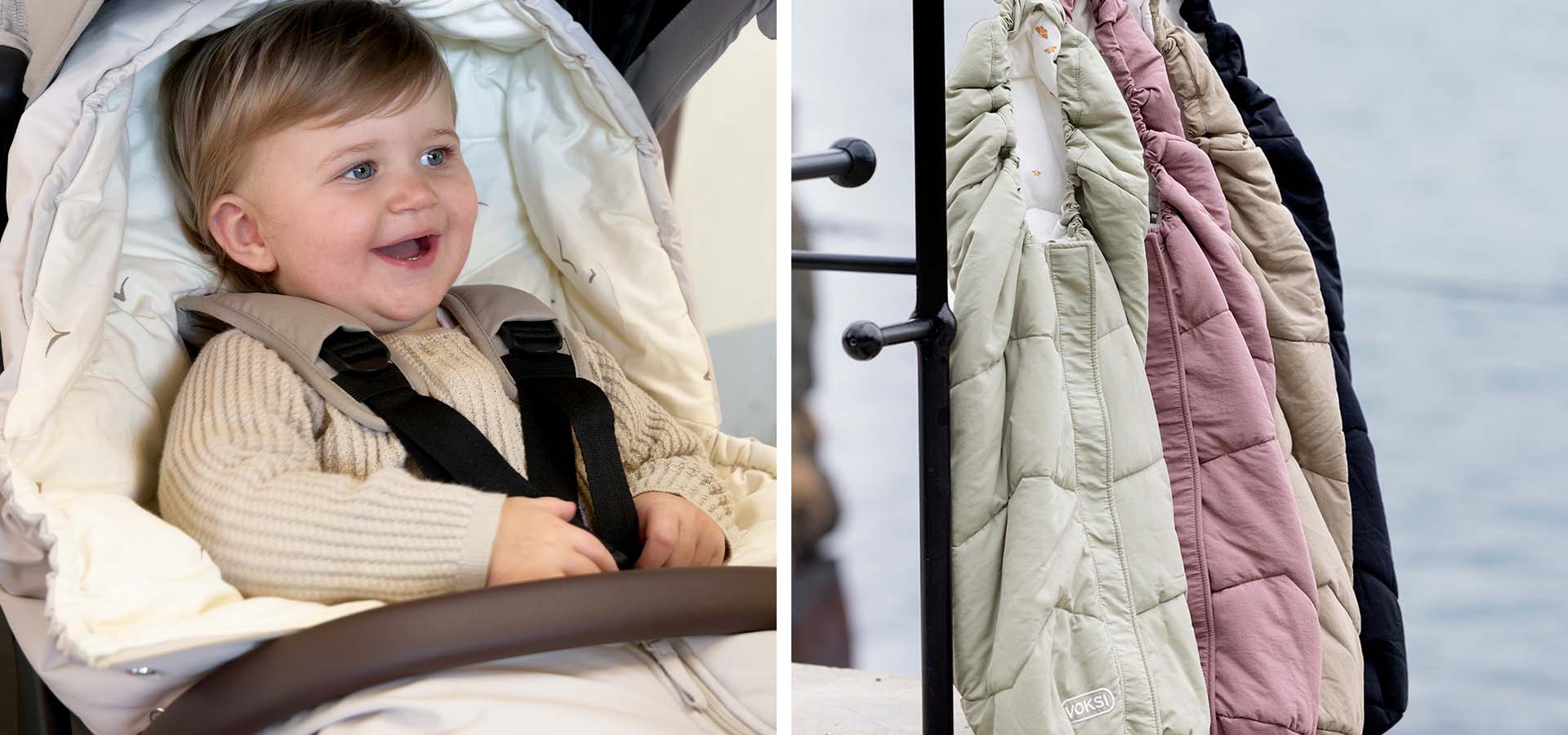 Baby im Kinderwagen mit lila Mütze, mehrere Fußsäcke hängen in einer Reihe.