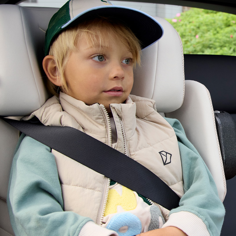 Glückliches Kind mit Sicherheitsgurt im Autositz.